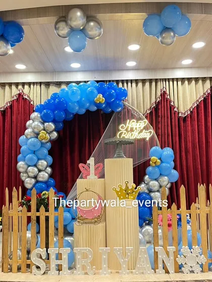 A blue and silver balloon ring on a stage. The picket fence and light-up name sign create a defined and attractive space for photos.
