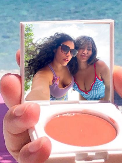 A creative selfie taken in the reflection of a blush compact. This is a fun, unique way to capture a moment with my bestie on the beach.