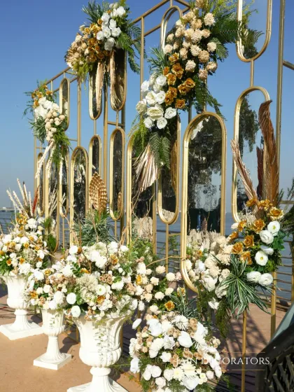 A modern and glamorous detail. This golden screen with mirrored panels is adorned with arrangements of white flowers and pampas grass, reflecting the seaside view behind it.