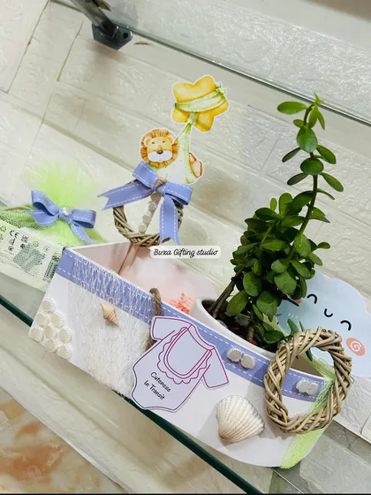 Set sail for a new adventure! This unique boat-shaped hamper with a jade planter and lilac accents is perfect for a nautical or sailor-themed baby shower.