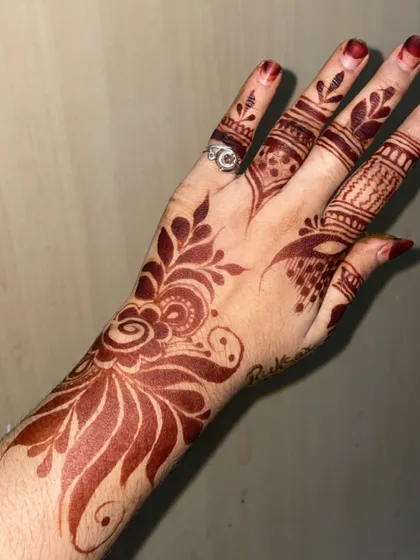 A beautiful example of a Gulf-style henna stain. The design features bold floral and leaf patterns with shaded areas, and the color is a striking dark reddish-brown.