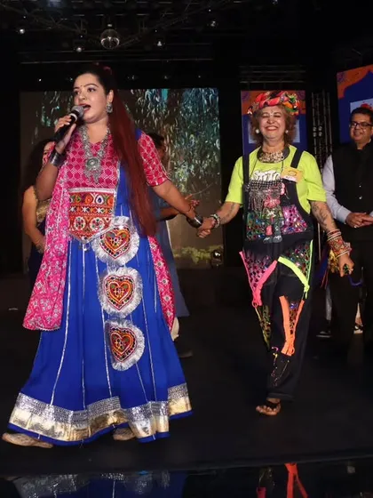 Holding hands with a guest on stage, creating a warm and inclusive atmosphere.