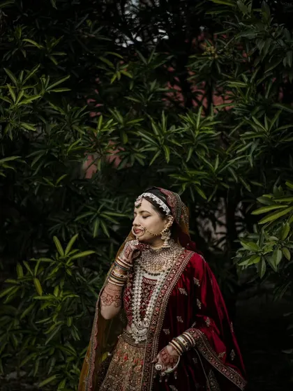 A candid-style portrait of a Muslim bride in a lush garden setting. Her natural expression and the soft light create a beautiful, serene image.