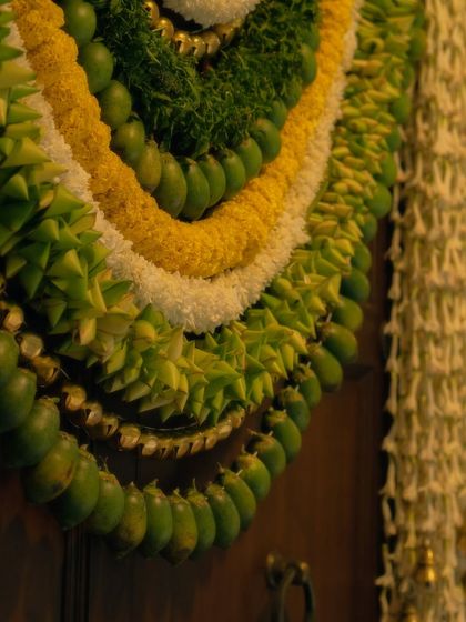 A close up of a custom designed floral toran. We used layers of intricately woven leaves, marigolds, and jasmine buds to create this piece, which served as a beautiful welcome accent on the main doorway.