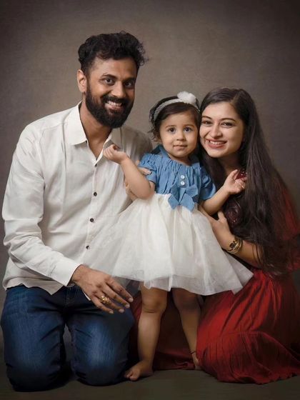 A kneeling family portrait creates a lovely, connected composition. The coordinated outfits and warm smiles make this a cherished memory.