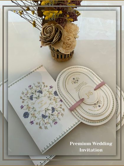 A premium wedding invitation set featuring a unique oval-shaped multi-layered card, held together by a personalized band. This modern design is perfect for contemporary couples.