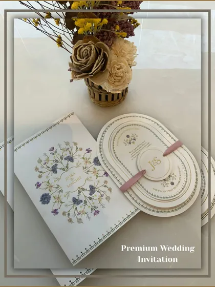 A premium wedding invitation set featuring a unique oval-shaped multi-layered card, held together by a personalized band. This modern design is perfect for contemporary couples.