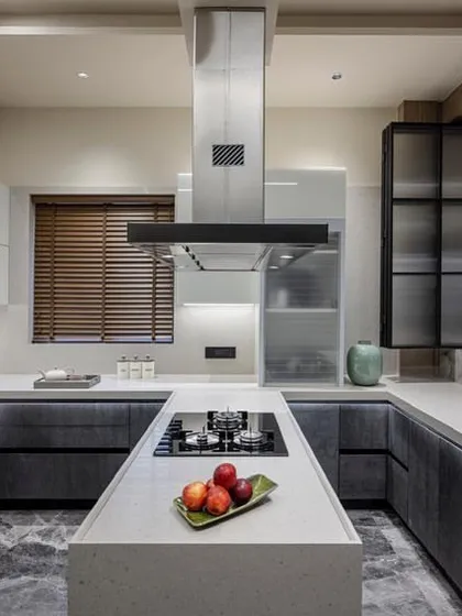 This U-shaped kitchen with a central island is a perfect example of a highly functional and social space. The design uses a mix of dark ceramic-finish cabinets and white high-gloss units.