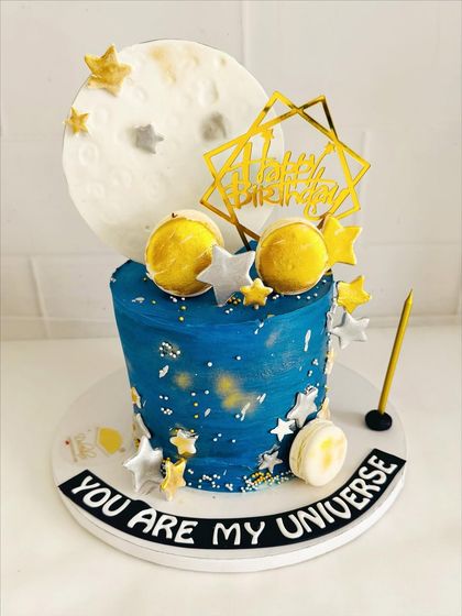 A "You Are My Universe" cake with a fondant moon, planets, and stars against a deep blue galaxy.