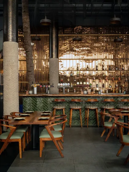 Every detail matters in creating the right mood. Here, the custom bar features a live edge wood countertop and a striking green subway tile fascia. The warm backlighting on the bottle display and the reflection on the polished columns create a sophisticated and inviting atmosphere for guests.