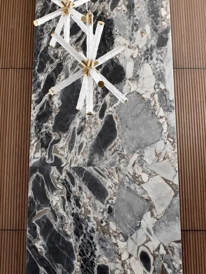 A stunning floor-to-ceiling accent wall that demonstrates our expertise in combining materials. A central slab of dramatic black and grey stone is flanked by warm, vertically fluted wood panels, creating a powerful focal point in this luxury space.