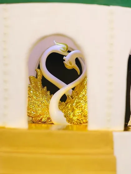 A detailed look at the centerpiece of our royal engagement cake, featuring two elegant swans forming a heart shape within a golden arch.
