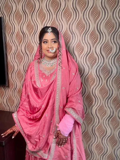 A full view of the bride in her simple yet elegant pink suit, perfect for a morning wedding ceremony.