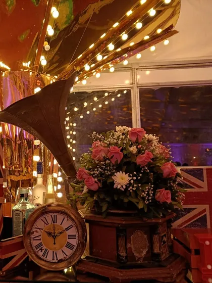 A classic gramophone horn and a vintage-style clock add to the Victorian-era ambiance. These details, combined with the warm lighting and floral arrangements, transport guests to a different time and place.