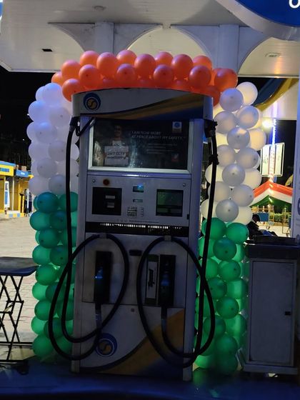 A close-up of a fuel dispenser framed with a tricolor balloon garland. This type of decoration is ideal for retail locations celebrating national holidays.