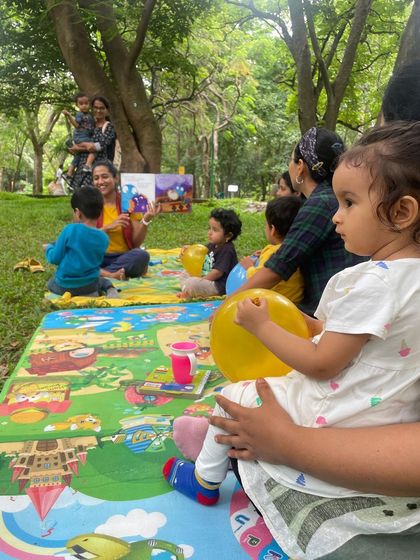 A sweet moment with a toddler holding a balloon, listening to a story. Our sessions are welcoming to even the youngest members of the family.