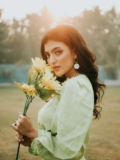 A companion shot to the hero image, this portrait features a direct gaze. The golden backlight and the sunflowers create a warm, inviting, and slightly vintage atmosphere.
