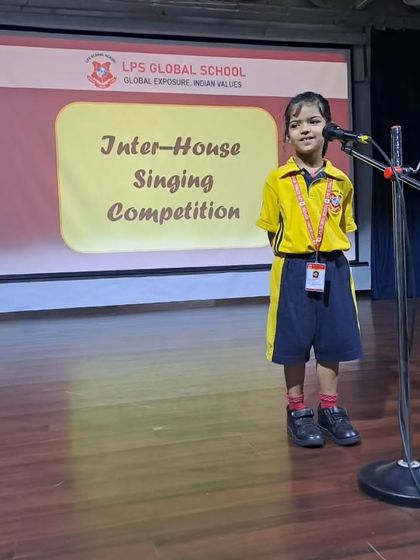 A student from the yellow house sings her heart out on stage, contributing to her team's points.
