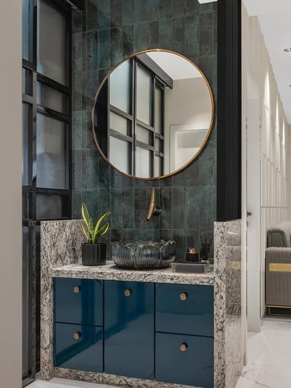 The powder room is designed to be a refreshing escape for guests. It features a stunning lotus-shaped vessel sink, soothing blue cabinetry, and a dark green tiled backsplash for a touch of luxury.