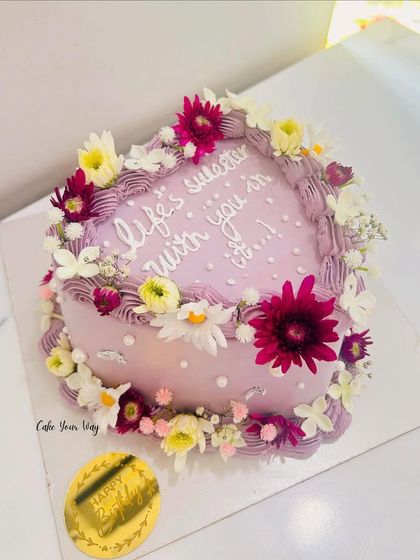 Love, flowers, and frosting. This heart-shaped cake with a sweet message is adorned with a wreath of fresh, colorful flowers.