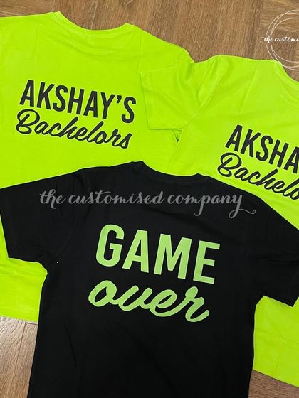 Get the bachelor party started with these fun, custom t-shirts. The groom's "Game Over" shirt contrasts with the groomsmen's neon green "Akshay's Bachelors" tees for a memorable look.