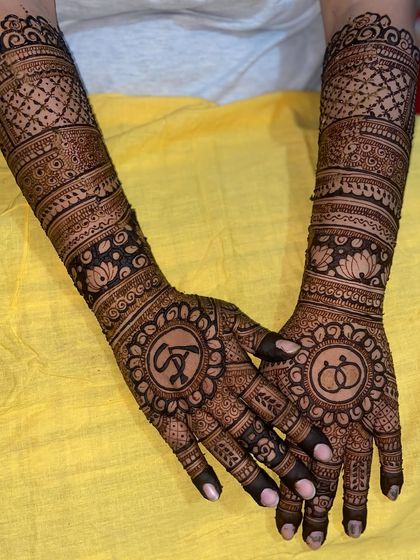 This design combines the couple's initials, 'AS', with the symbol of intertwined rings, all woven into a traditional full-hand mehandi.