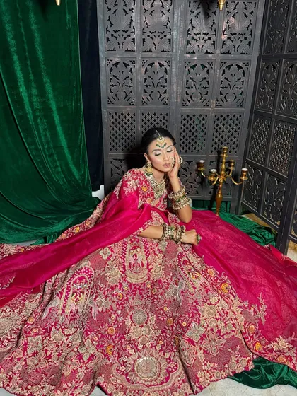 A full-length view of a magnificent bridal lehenga. The makeup is designed to balance the grandeur of the outfit, with a focus on a radiant complexion and striking eyes.