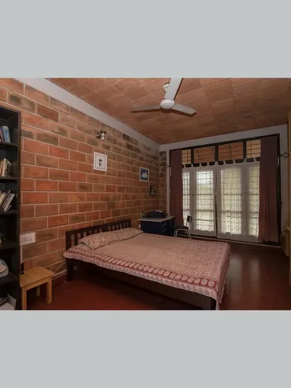 A bedroom with a built-in bookshelf, combining storage and study space within a calm, earthy environment.