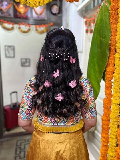 A whimsical Haldi hairstyle featuring butterfly clips and pearls scattered through soft curls. This is a great example of a fun, personalized touch.