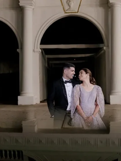 A wide shot of the couple framed by grand arches at night. This portrait has a classic, almost regal feel, like a scene from a timeless romance set in a palace.