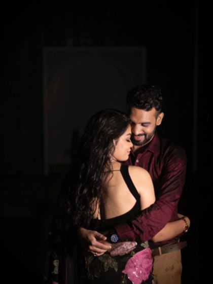 A romantic and intimate shot from behind, focusing on the couple's embrace in a dimly lit setting.