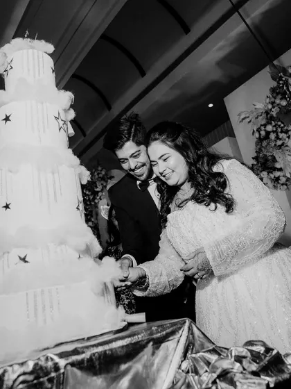 The couple cutting their magnificent, star-themed wedding cake. This black and white shot focuses on their shared action, a classic and happy moment from their Christian wedding reception.