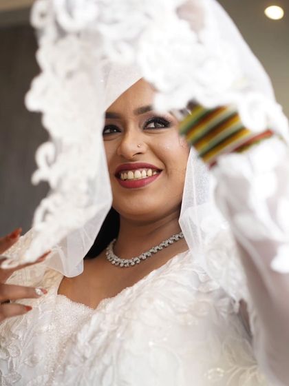 A beautiful close-up of the bride through her veil. The soft focus highlights her happy expression and the delicate details of her makeup.