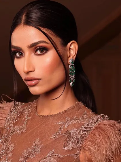 A close-up of a dramatic editorial look. The makeup features a bronze smokey eye and a sculpted cheek, creating a look that is both fierce and beautiful.