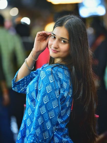 A beautiful solo portrait with a soft, engaging smile. The colorful bokeh from the streetlights adds a dreamy quality to this lovely night shot.
