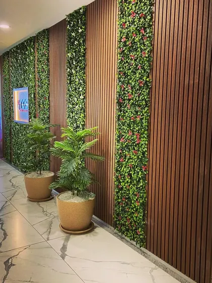 We designed this hallway by integrating vertical strips of artificial greenery with dark wood louvered panels. This combination of textures adds depth and a modern, natural feel to the commercial space.