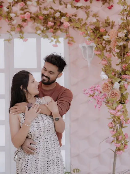 A tender moment against a romantic floral backdrop. The soft pink tones and the couple's gentle embrace create a dreamy and affectionate pre-wedding portrait.