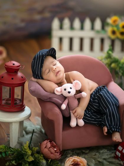 Styled with a cute striped cap, this baby is hugging a tiny mouse plushie while napping in our village-themed setup.
