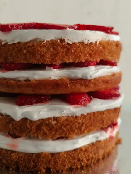 A side view of the layered strawberry cake, showing the generous layers of fresh cream and my homemade strawberry compote between the soft vanilla sponge.