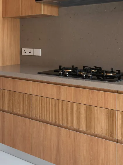 The texture of the fluted wood drawers adds a layer of subtle detail to this otherwise minimalist kitchen. It’s a quiet touch that brings character and a sense of craftsmanship to the space, proving that simplicity can be rich in detail.