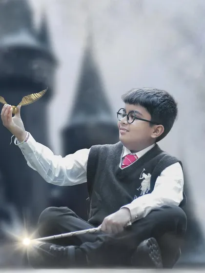 In this enchanting Harry Potter portrait, the young boy sits cross-legged, holding a glowing wand and admiring the Golden Snitch.