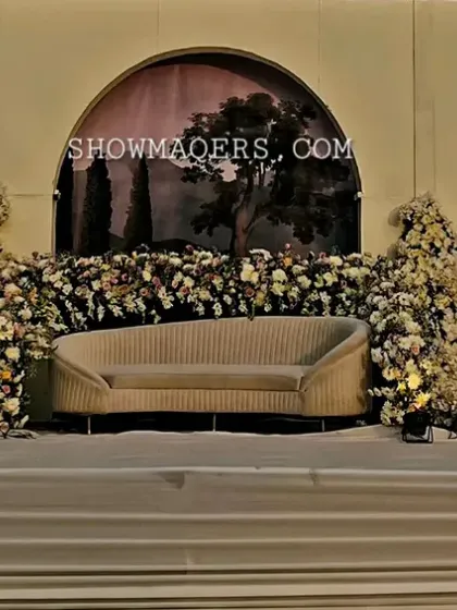 A stunning stage backdrop with arched panels and overflowing white floral arrangements, creating a sophisticated and romantic setting for the couple.
