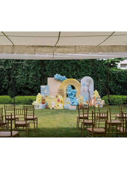 A wide shot of the Winnie the Pooh party setup in a beautiful garden. The decor is arranged perfectly for guest seating and photos, creating a wonderful party atmosphere.