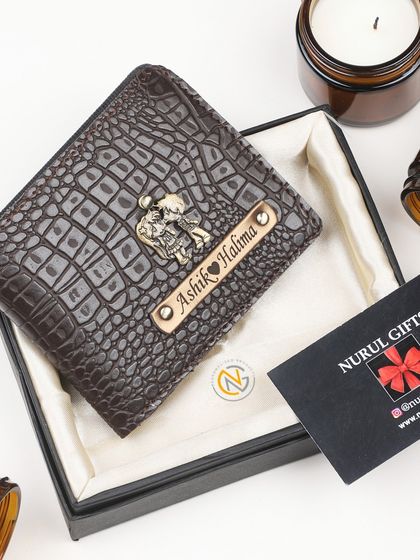 A dark brown crocodile leather wallet personalized with a couple charm, making it a sweet gift for a partner.