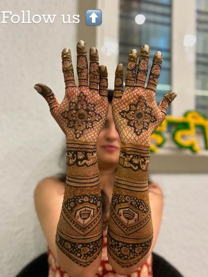 This bride is showing off her beautiful engagement mehndi, which features elegant mandalas on the palms and intricate patterns on the arms.