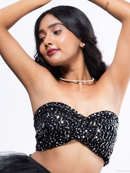 A graceful pose in a sequined top, with the model's arms raised.