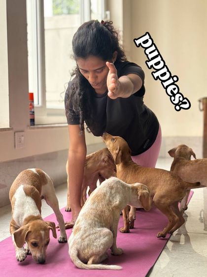 A yoga instructor is surrounded by a group of curious puppies during a class, showing the fun and chaotic nature of our sessions.
