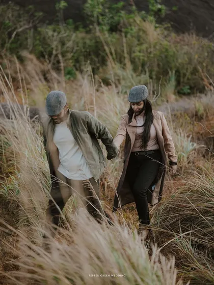 The couple walks through tall grass, hand in hand, creating a sense of journey and togetherness in their adventurous pre-wedding session.