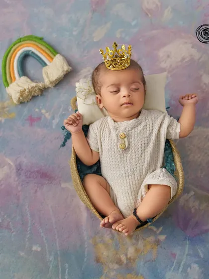 A little prince dreaming of rainbows. The tiny crown and colorful rainbow prop add a touch of magic and hope to this sweet newborn portrait.