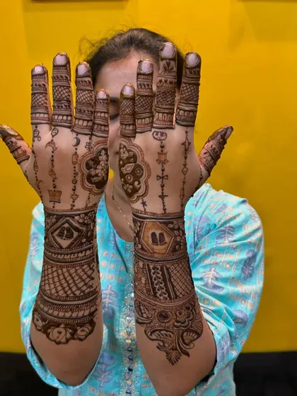 A different style of baby shower mehndi, focusing on geometric patterns and hanging charms.